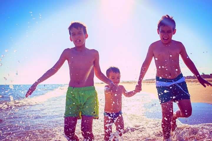 três crianças brincando na praia