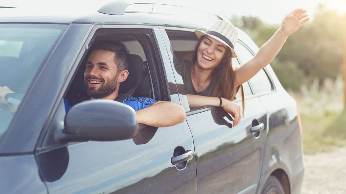 casal feliz e animado, viajando de carro para Trancoso